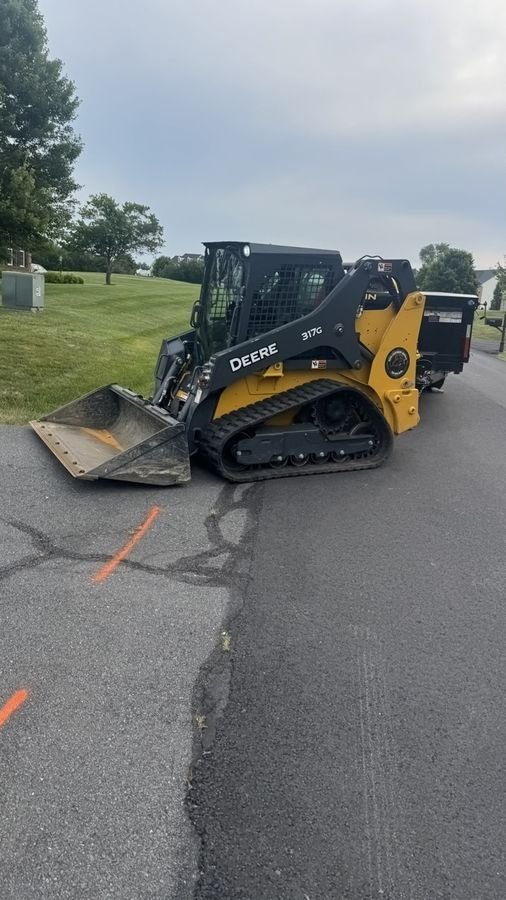 John Deere 317G loading material on a residential driveway job